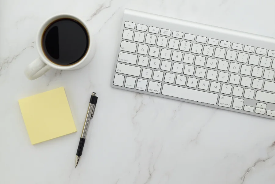 A tidy desk with a coffee cup and keyboard on a marble surface